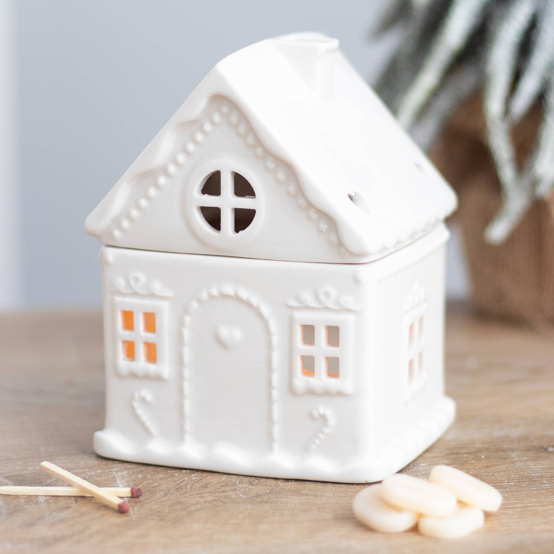 White ceramic house-shaped container on a wooden surface with matches