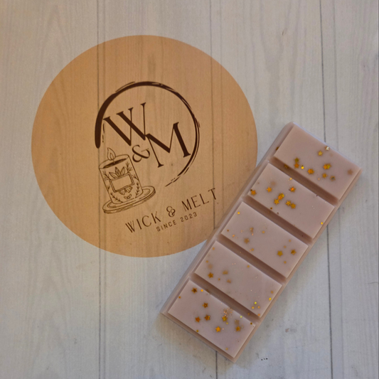 Wax melts with gold specks on a wooden surface with 'Wick & Melt' branding.