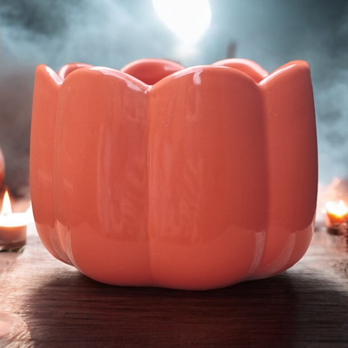 Pumpkin-shaped candle holder on a table with candles and pumpkins in a Halloween-themed setting.